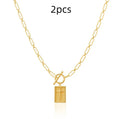 Gold electroplated stainless steel clip chain necklace with cross and square geometric pendant on white background