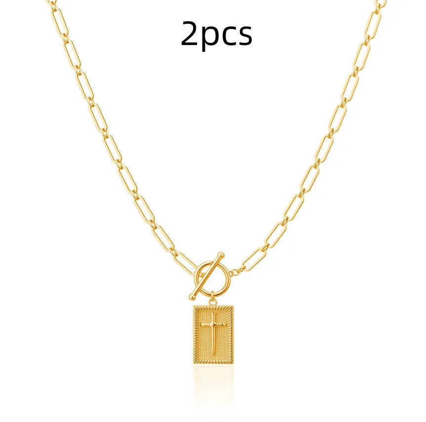 Gold electroplated stainless steel clip chain necklace with cross and square geometric pendant on white background