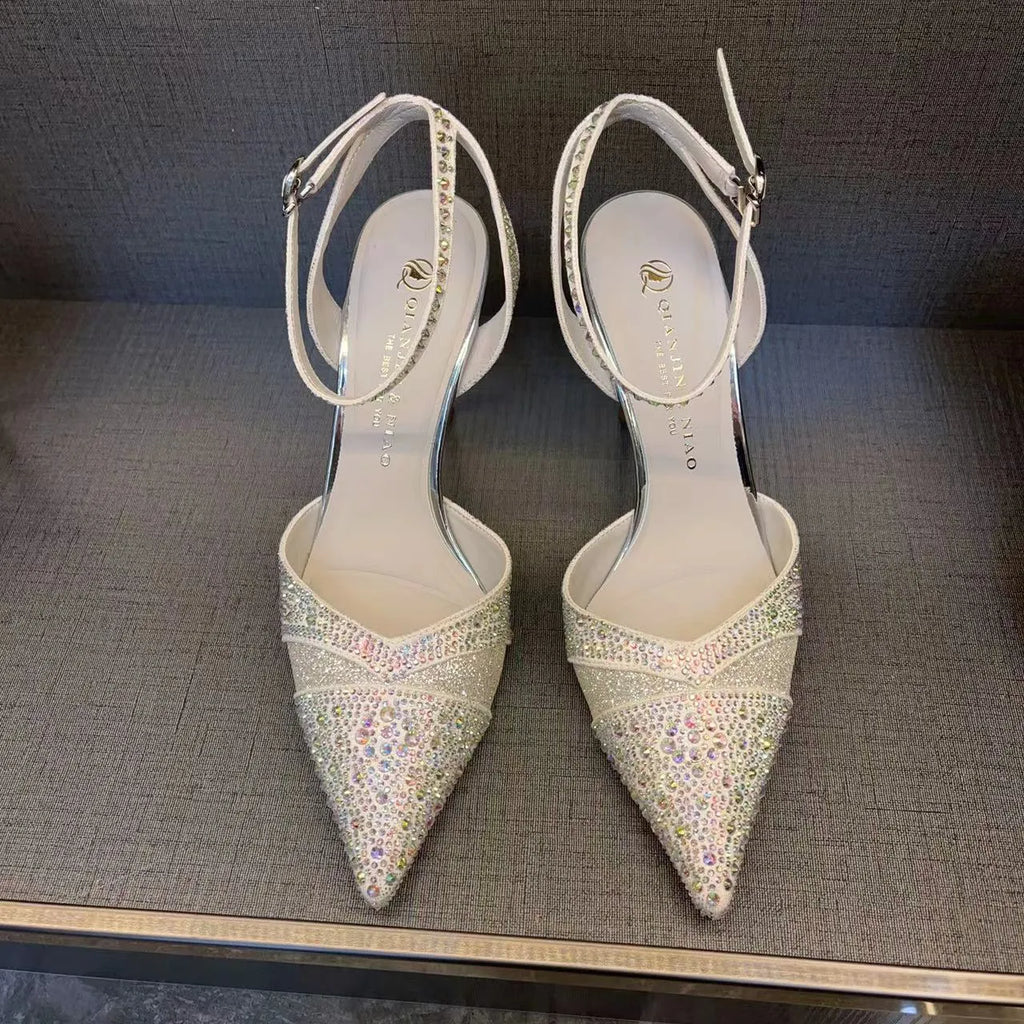 Women's silver high heel shoe with stiletto heel, pointed toe, and red sole on a white background.