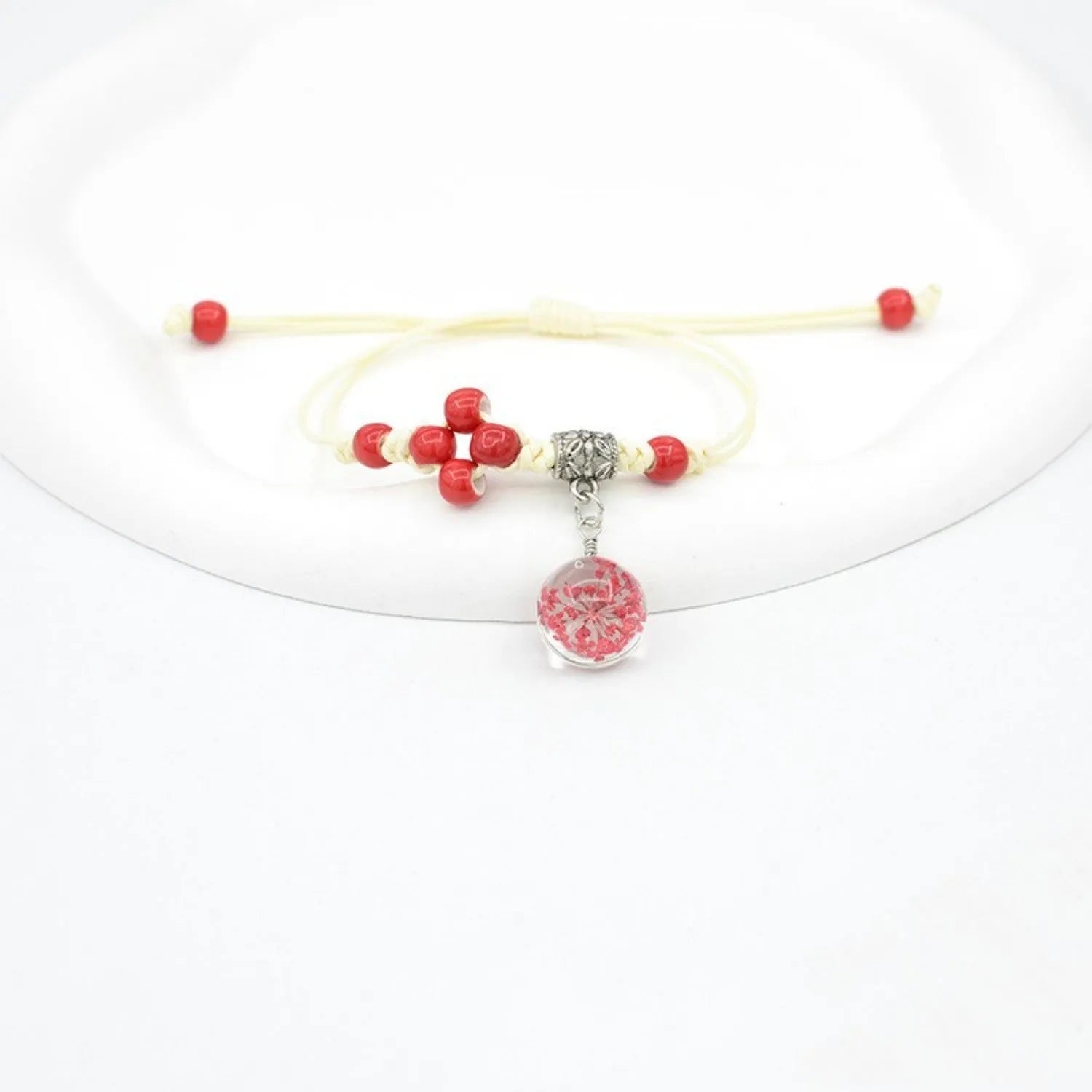 Close-up of a hand-woven glass bracelet with large beads containing real dried flowers and a lace design.