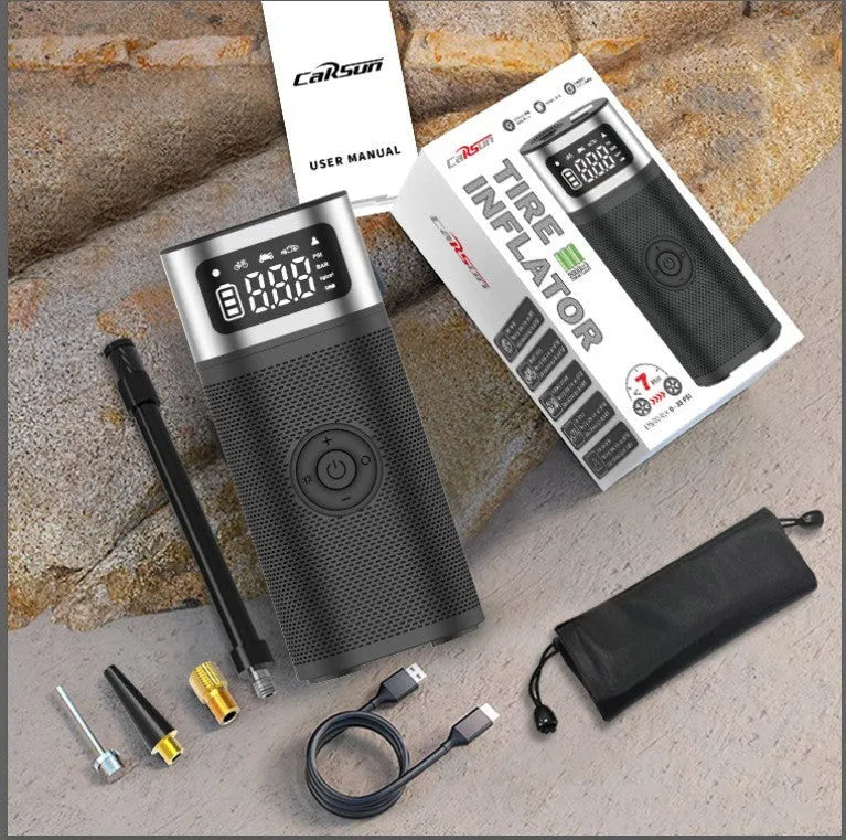 Black portable wireless car air pump with a digital display, inflation hose, and a set of nozzles on a black background.
