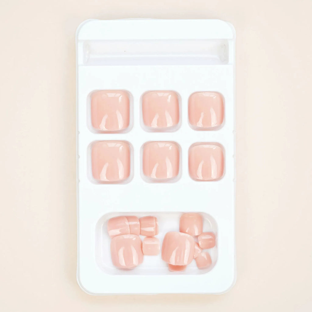 Set of ten skin-colour plastic artificial toenails and a bottle of glue for pedicure enhancement.