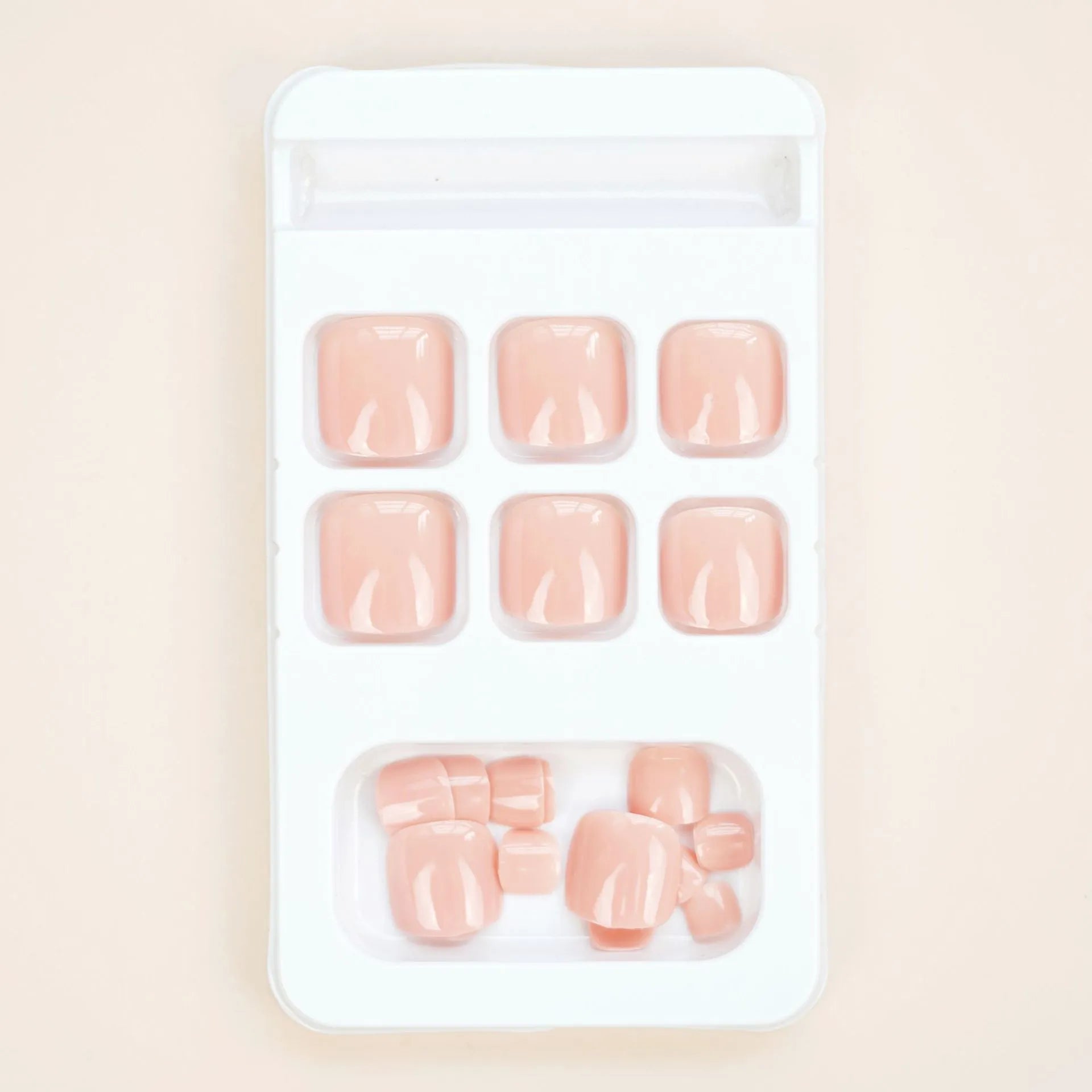 Set of ten skin-colour plastic artificial toenails and a bottle of glue for pedicure enhancement.