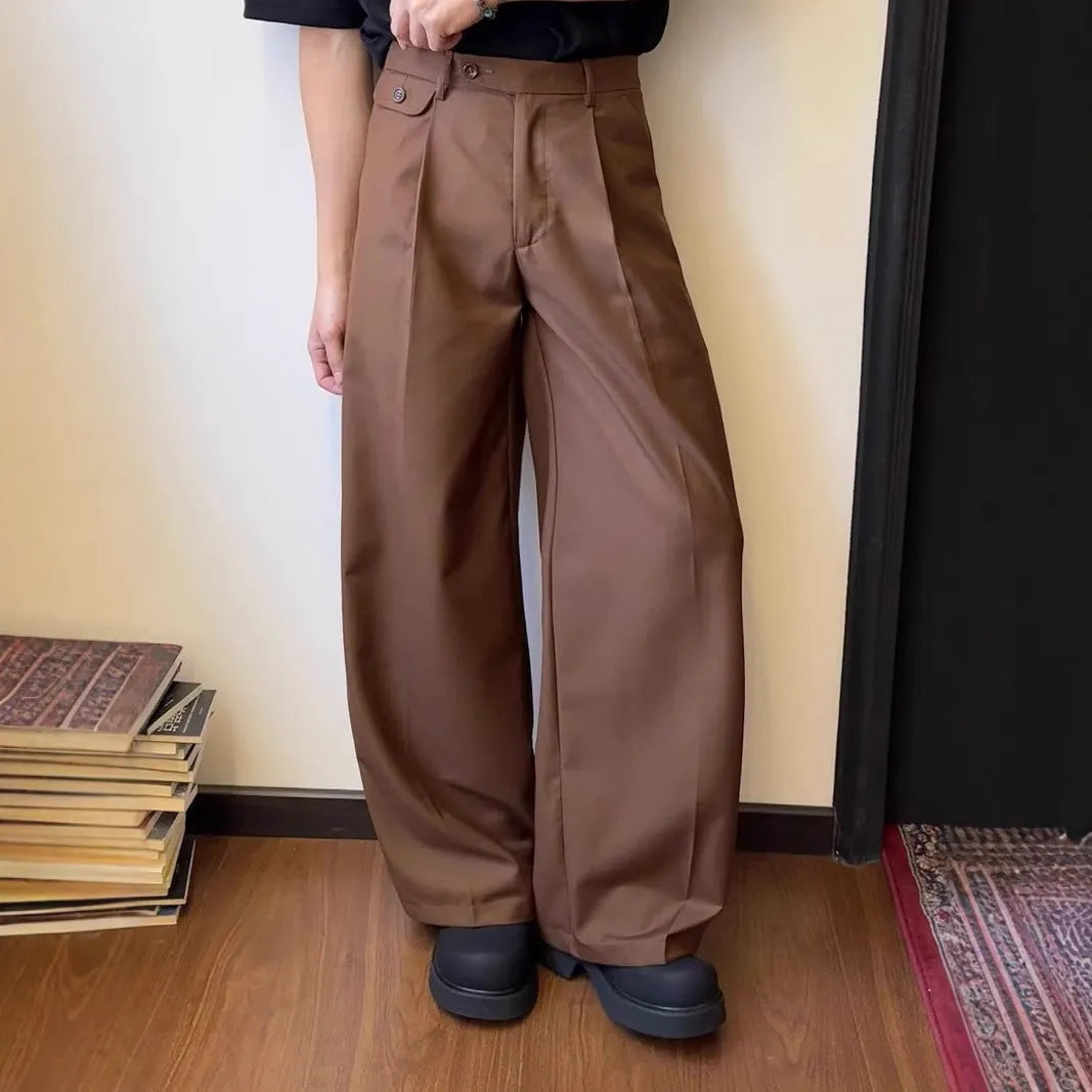Men's brown straight-leg wide-drape trousers on a hanger, showing loose fit.