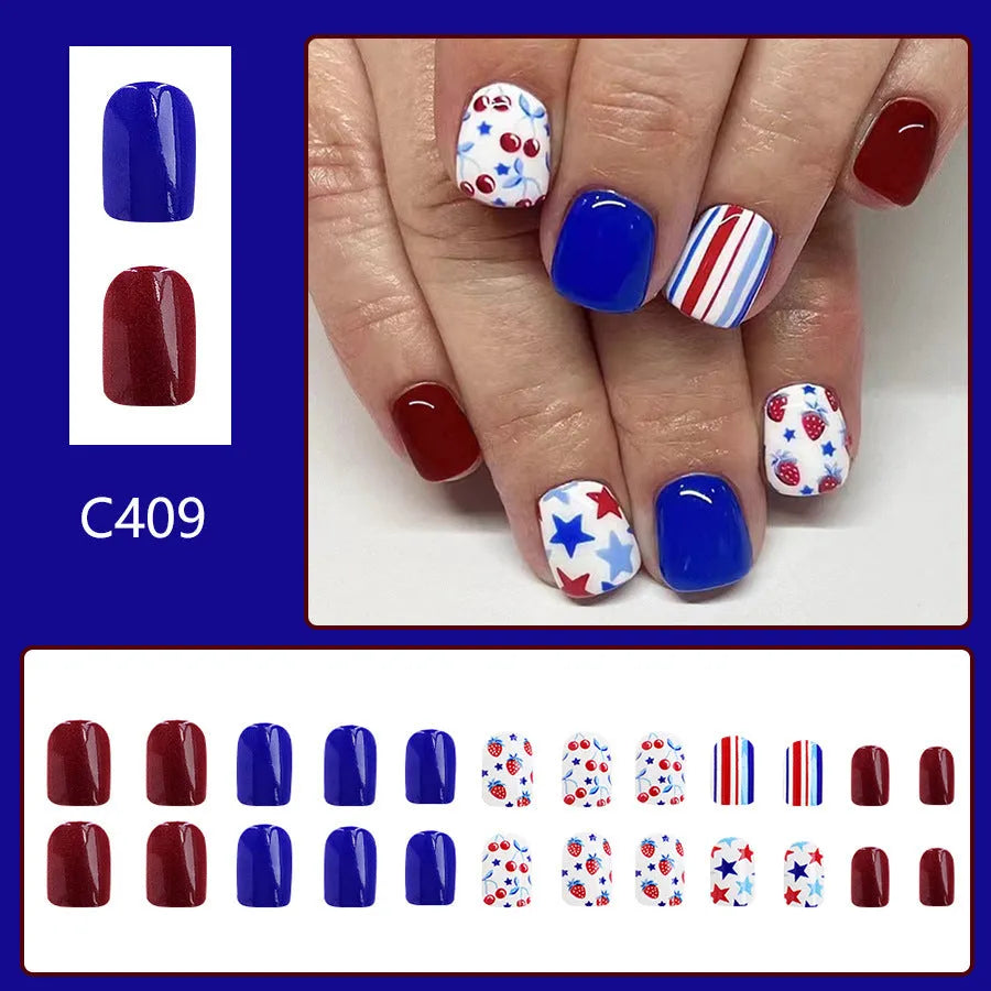 Short glossy false nails with strawberry and cherry pattern on red and blue background.