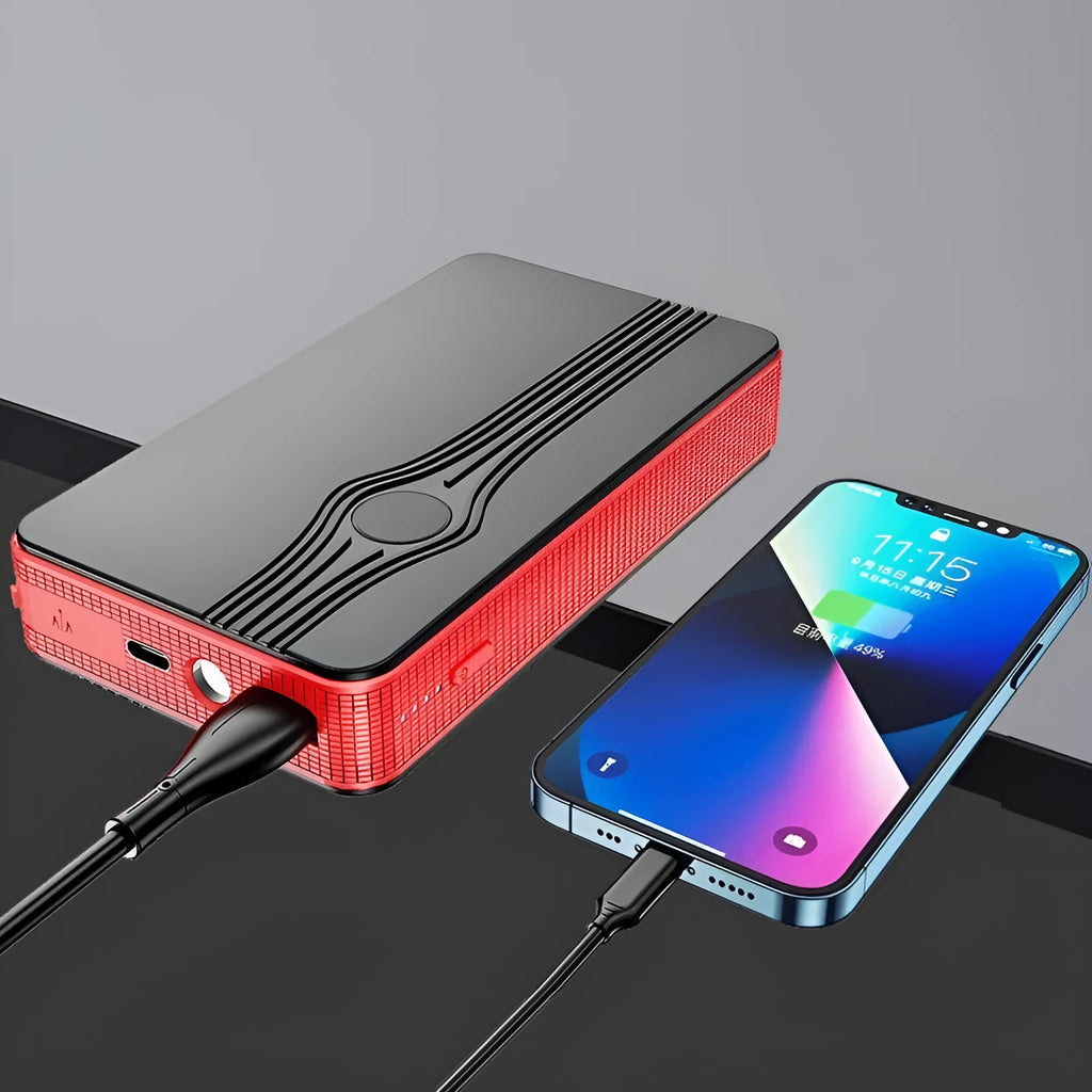 Red K4-E car jump starter power bank with display, shown next to a data cable on a dark surface.