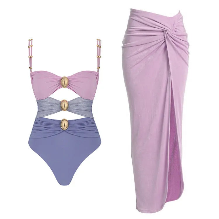 Women's solid colour one-piece swimsuit with gold buttons and a matching skirt.