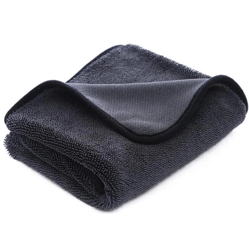 Grey braided car cleaning towel with red edge trim shown drying a car windscreen.