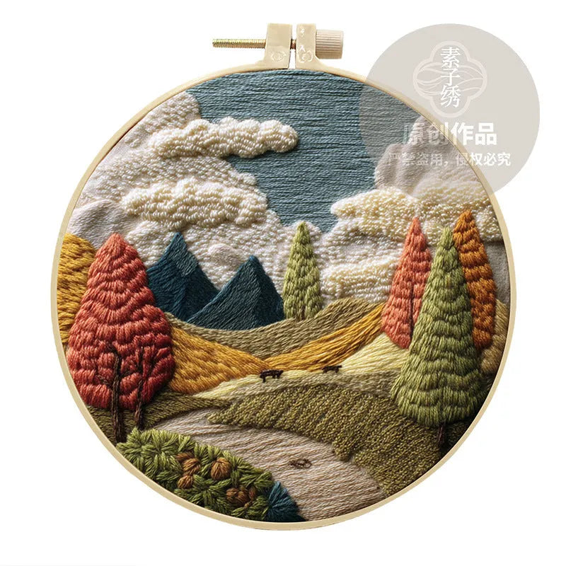 Embroidery DIY kit with bamboo frame, cotton fabric printed with a landscape scene, threads, and needles laid out