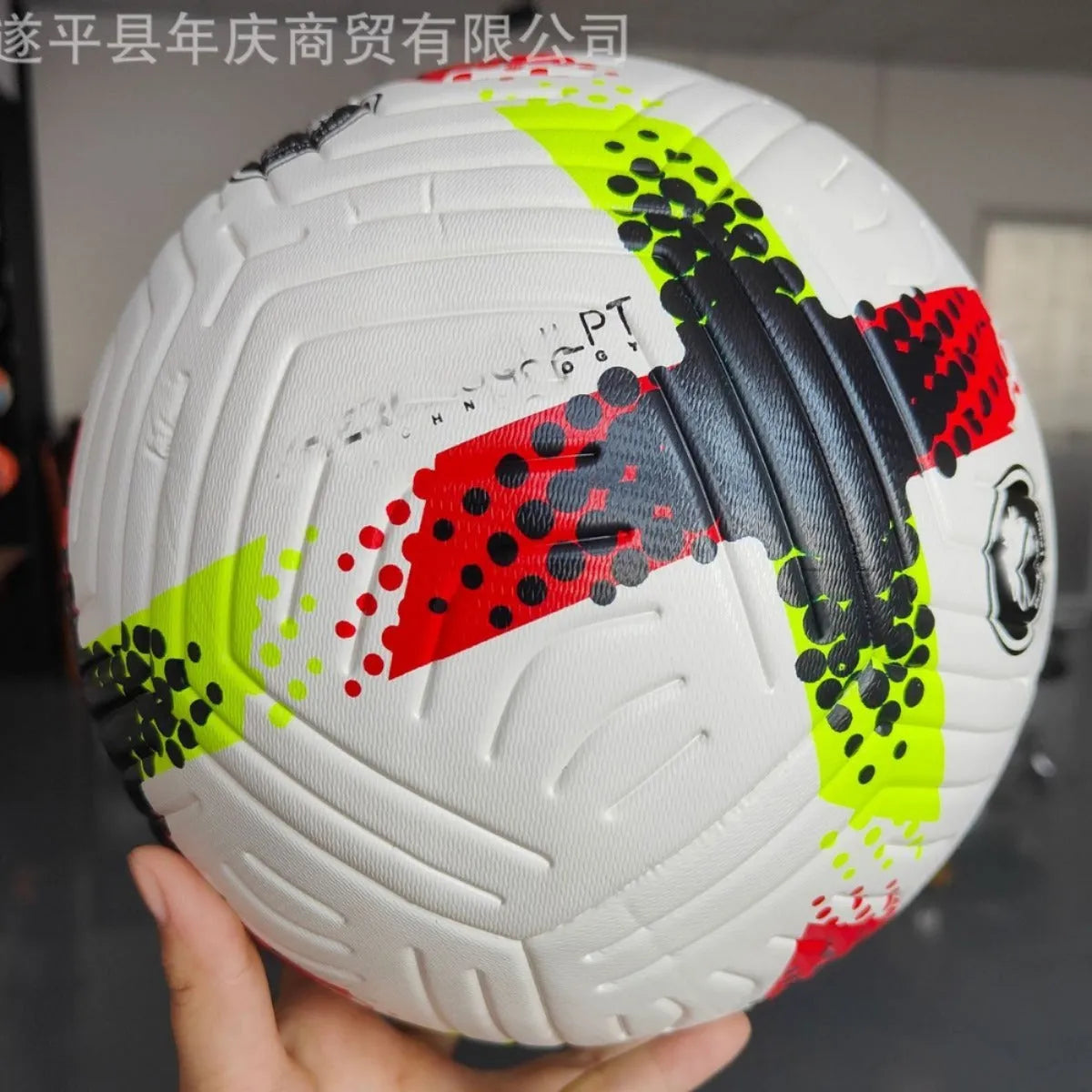 Fluorescent green Size 5 football with seamless thermal adhesive patches on a green pitch.