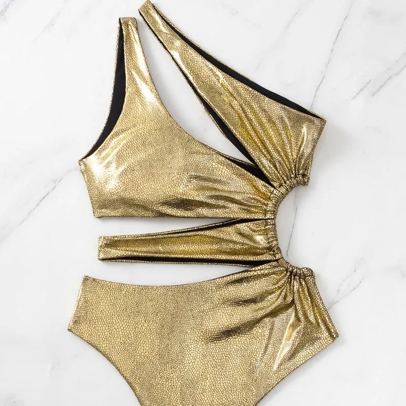 Women's gold one-piece backless swimsuit made from spandex, shown on a model.
