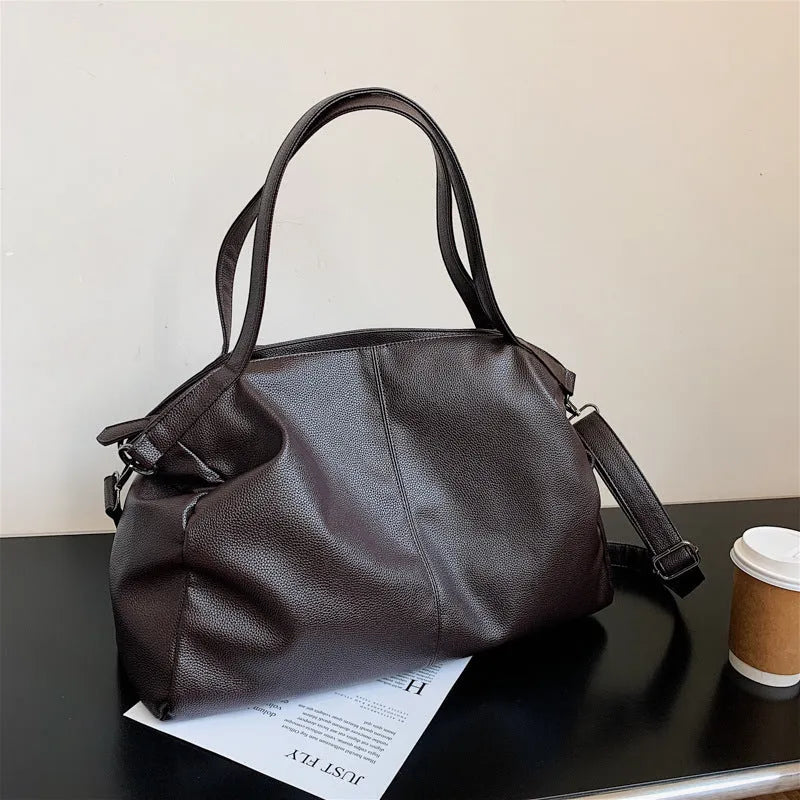 Large horizontal soft PU messenger bag in black with zip opening and long shoulder strap.