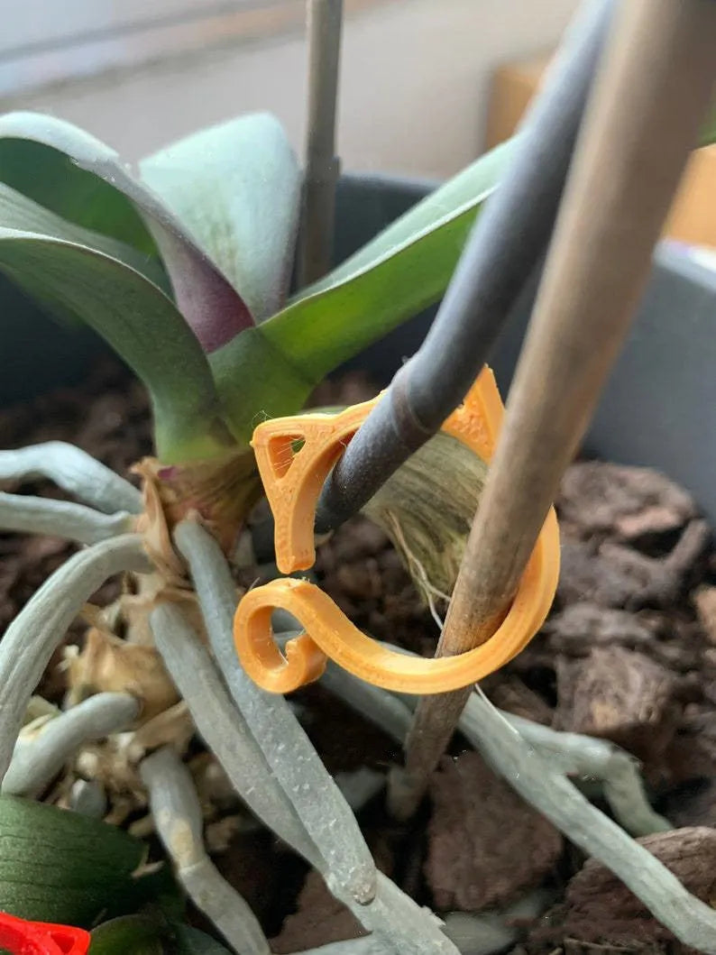 Decorative red plastic cat-shaped clip for gardening plant support.