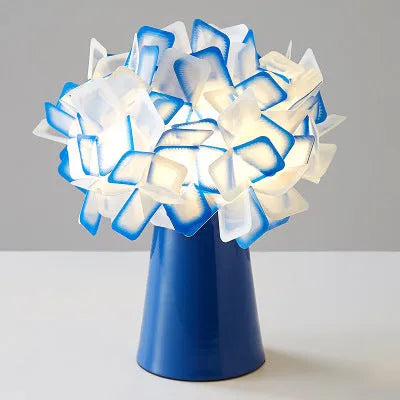Nordic style decorative table lamp with metal base in a choice of six colours on a wooden bedside table.