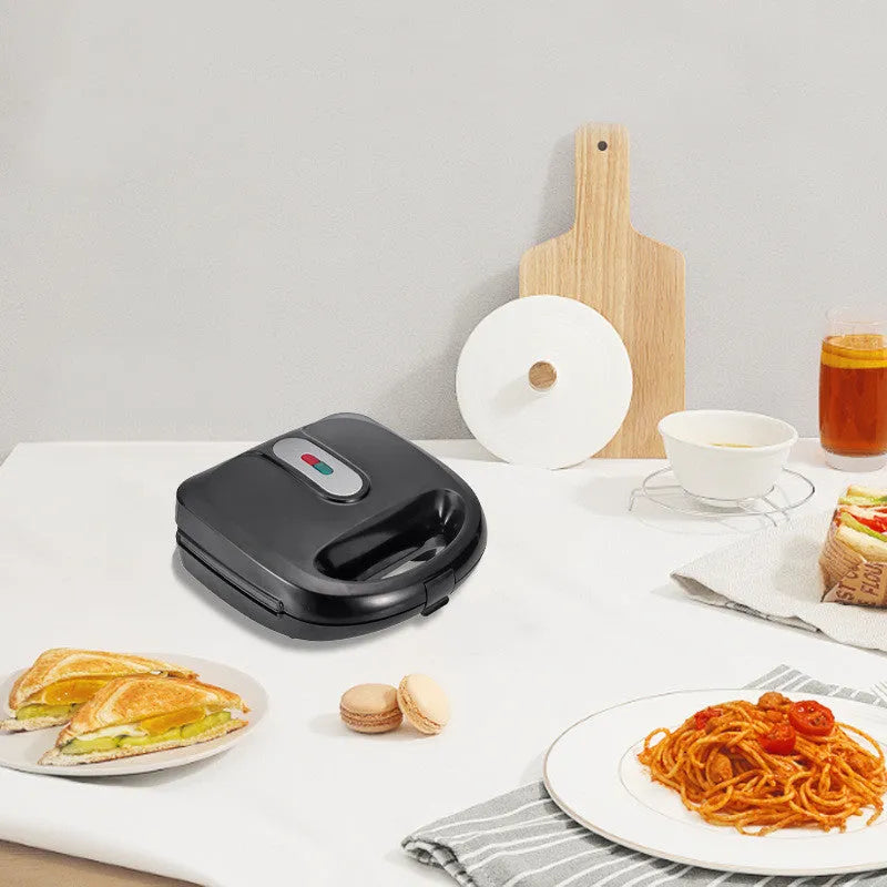 Black double-sided electric sandwich pan with stainless steel lid on a kitchen counter.