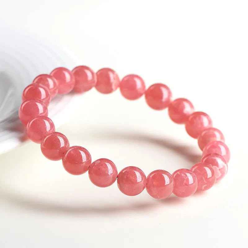 Women's red crystal bracelet with a geometric longevity lock clasp on a wrist.