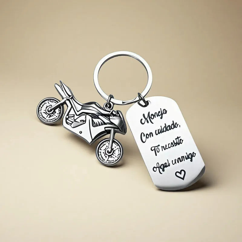 Stainless steel motorcycle keychain with a dark flannel storage pouch on a grey background.