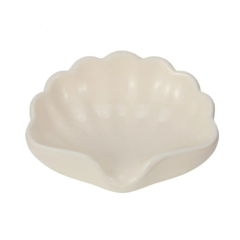 White or pink plastic shell-shaped soap dish for bathroom use.