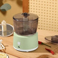 White and light green mini electric meat grinder with stainless steel blade on kitchen counter