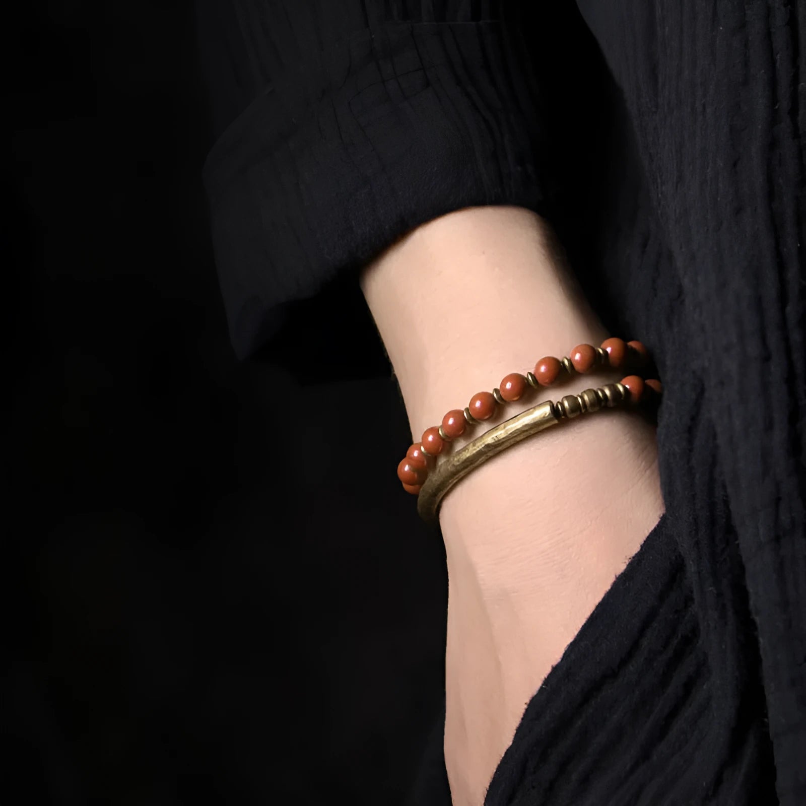 Layered retro ethnic bracelet for men and women with stone beads and brass accents on a wrist.