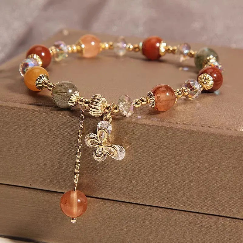 Colourful hair crystal bracelet with cat's paw, flower, butterfly, and coin purse charms on an adjustable band.