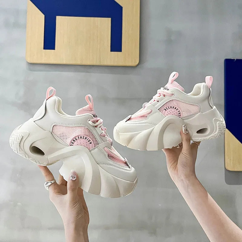 Women's pink casual sneakers with a cross strap, thick rubber sole, and mesh lining on a white background.