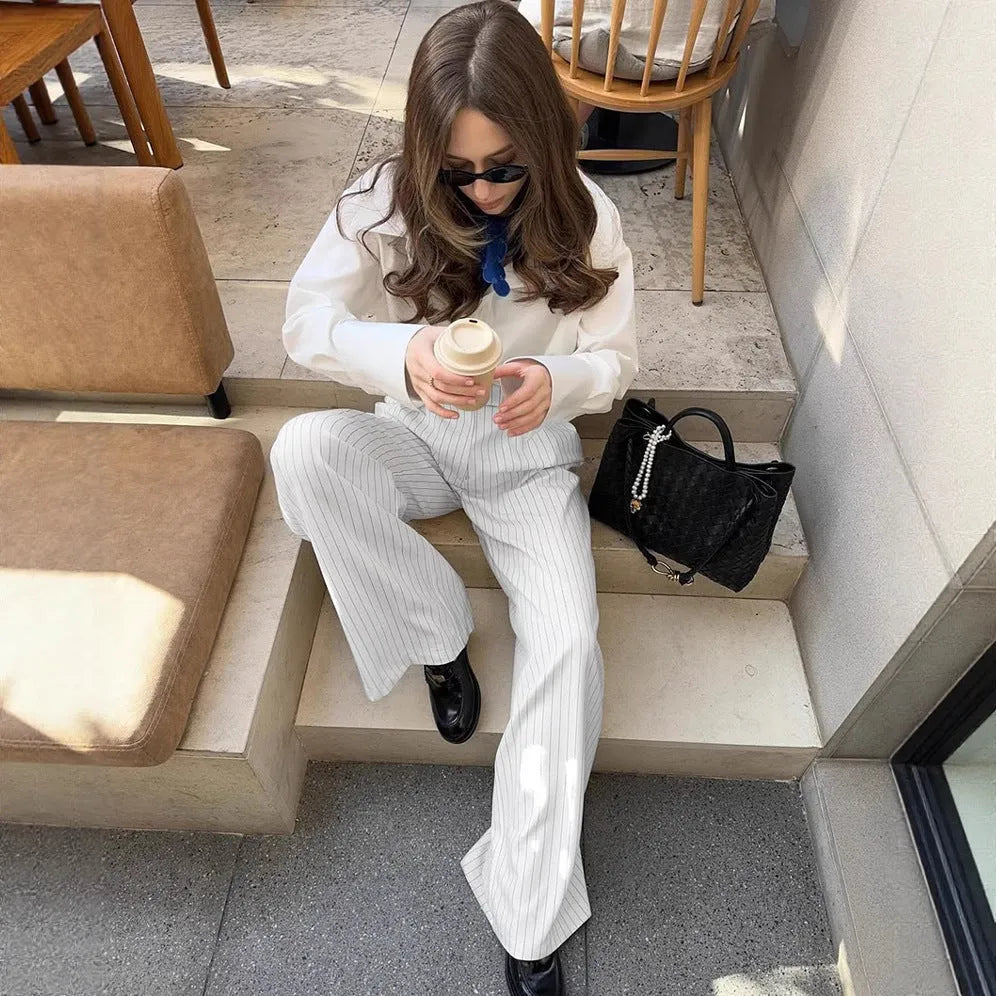 Women's white striped wide-leg trousers with front zipper closure on hanger