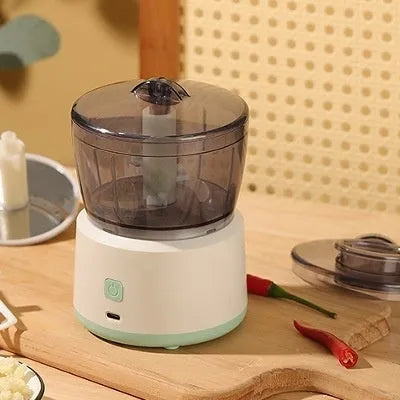 White and light green mini electric meat grinder with stainless steel blade on kitchen counter