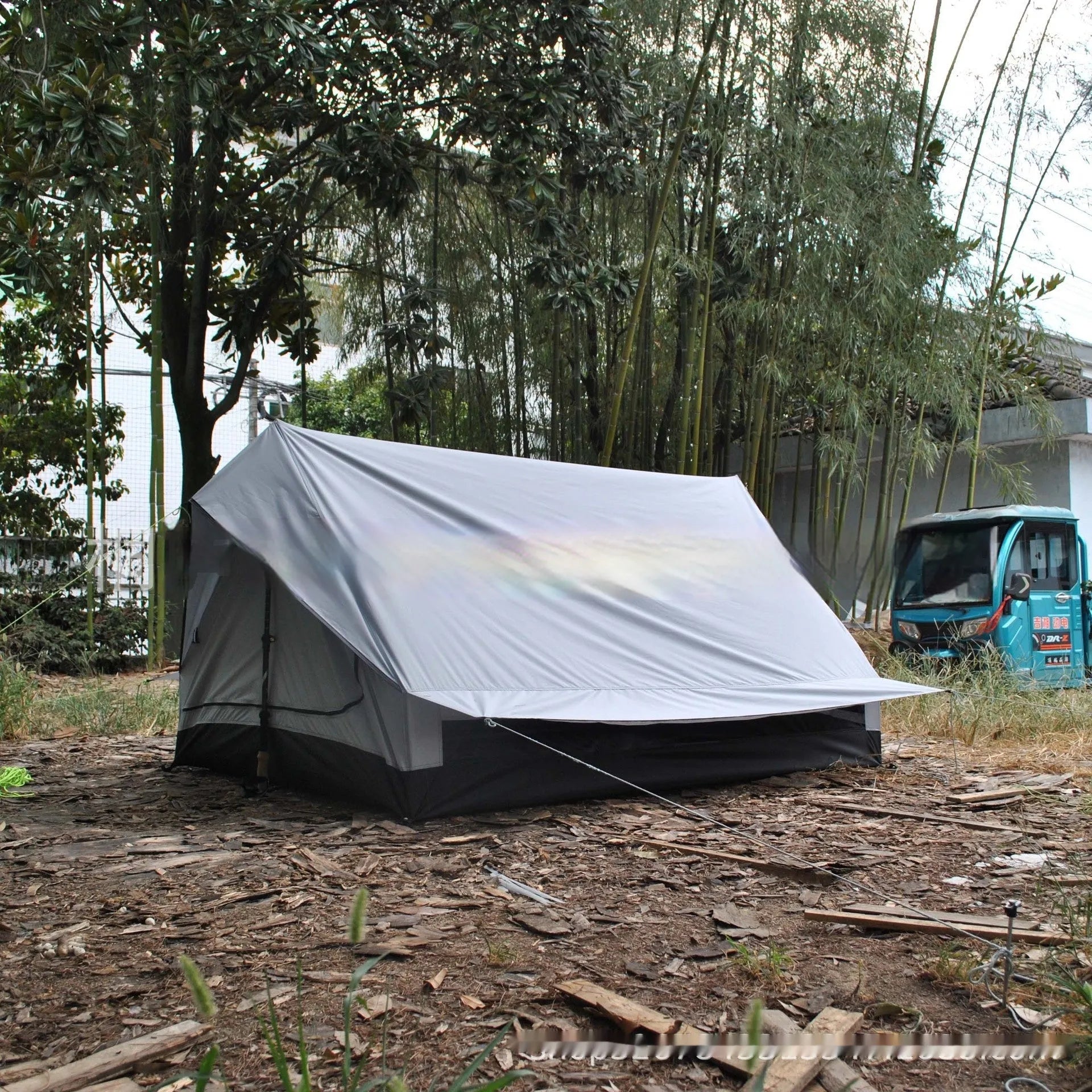 Brown or white A-line pole-free cabin tent for hiking, shown packed and pitched.