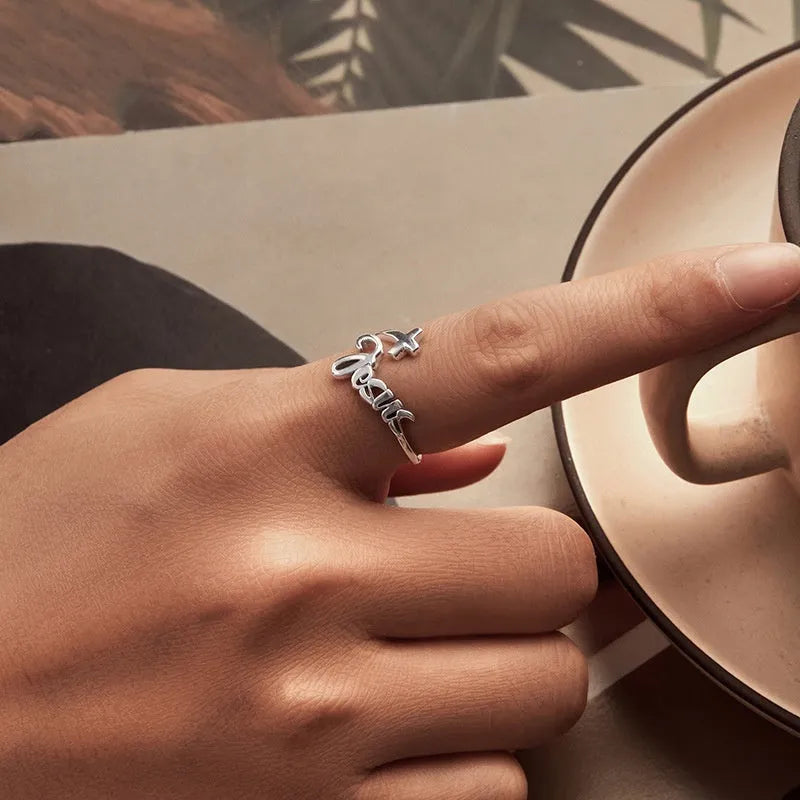 S925 sterling silver cross letter open ring with oxidised finish and adjustable opening on neutral background