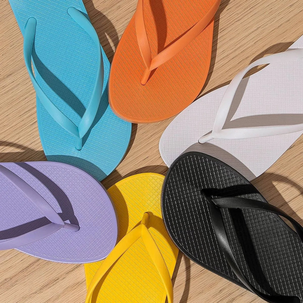 Foldable flat slippers with hollow-out design and non-slip PVC soles in orange, purple, black, or white.