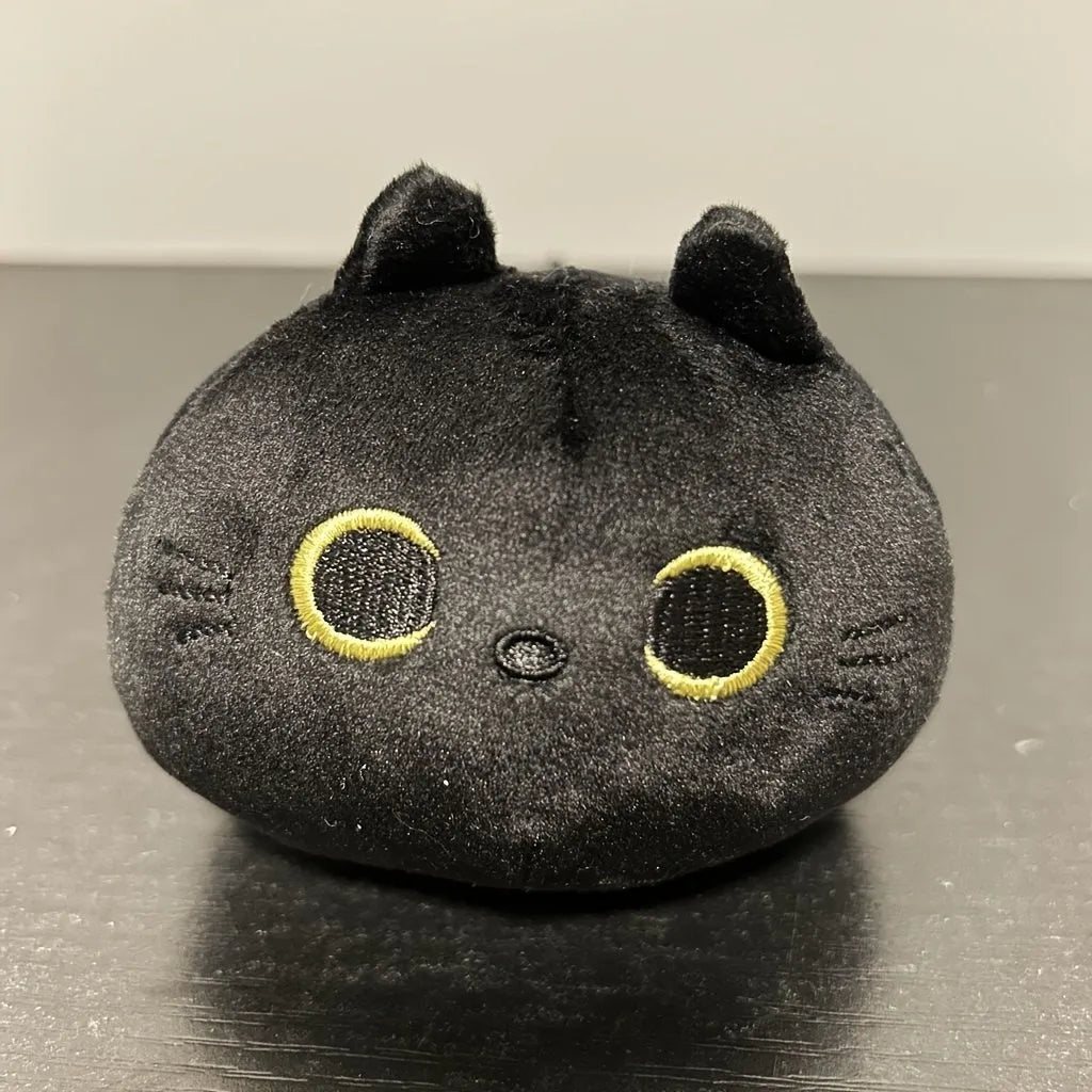 Black cat plush toy stuffed animal sitting as a soft pillow cushion on a sofa.
