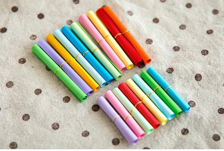 Multi-coloured mini paper scrolls in various sizes with metal eyelets for hanging.
