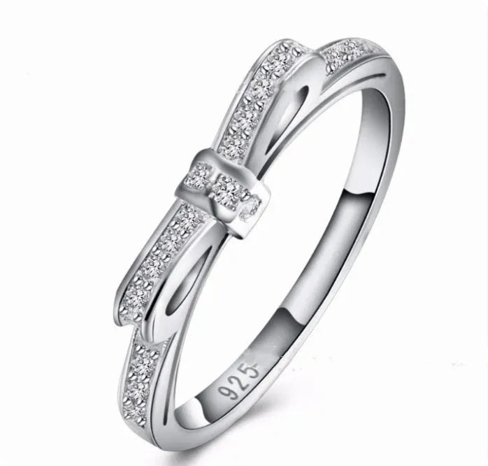 Silver bow-shaped ring with rhinestone and zircon crystal details on a model finger.