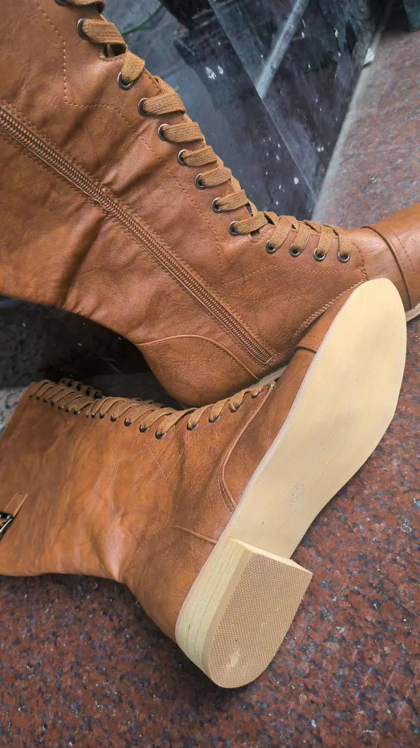 Women's black knee-high boots with a cross strap detail on the shaft, made of artificial PU leather.