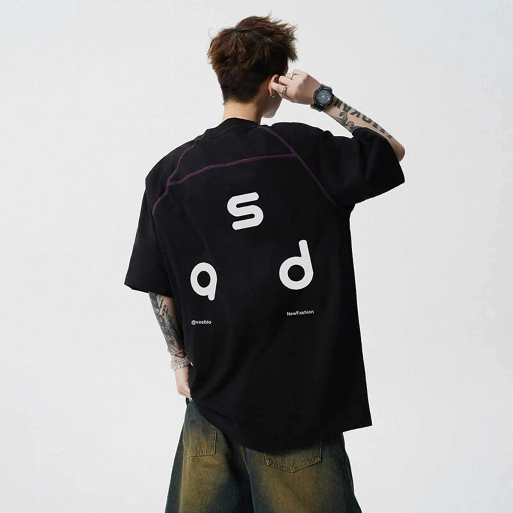 Man wearing a black loose-fit cotton t-shirt with a white letter print on the front.