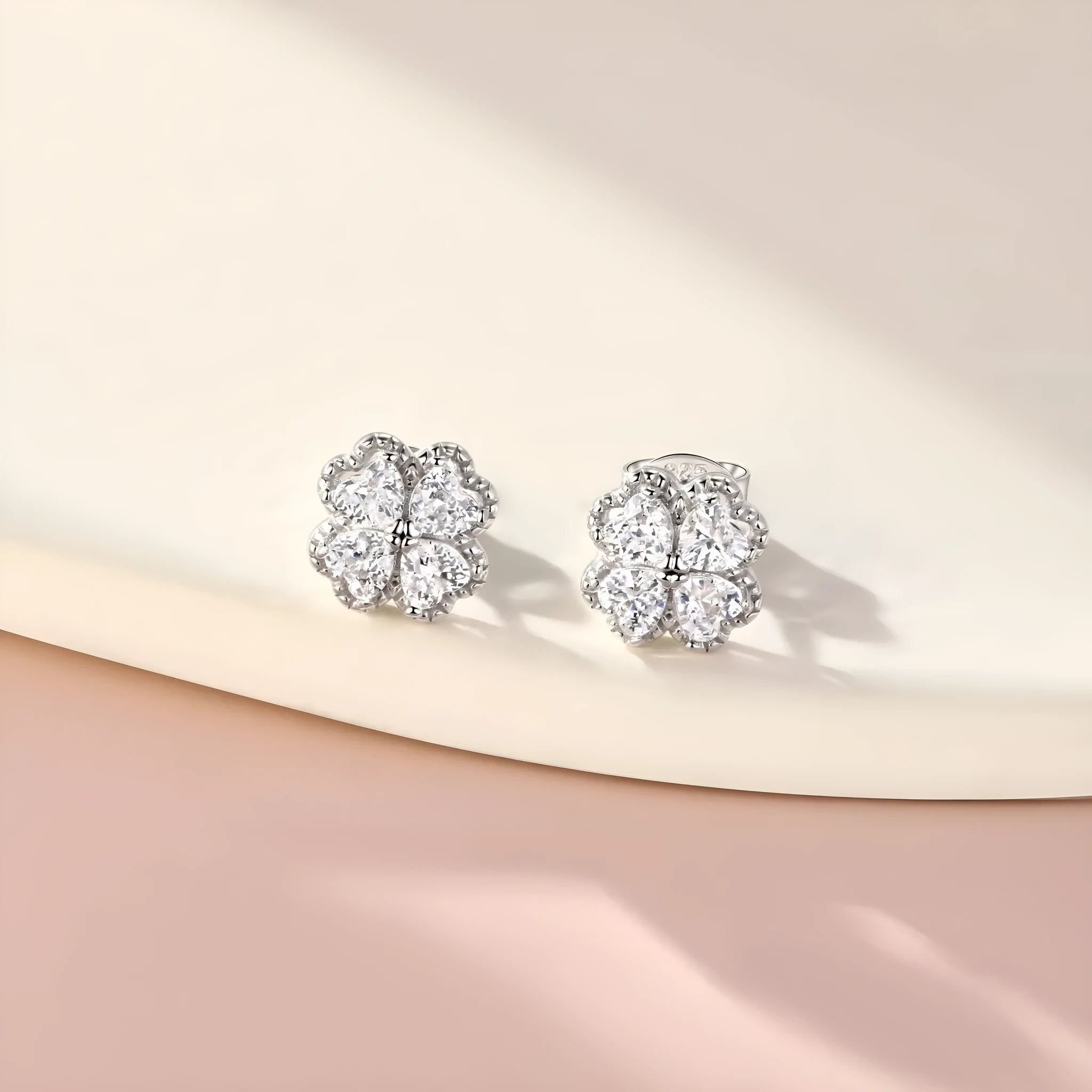 Pair of heart-shaped silver earrings with a four-leaf clover design and zircon stones.