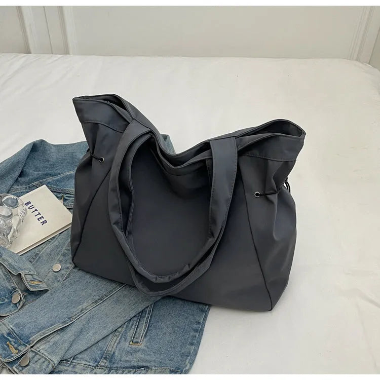 A foldable Oxford cloth commuter shoulder tote bag shown in one of five colours: black, brown, dark gray, light gray, or purple.