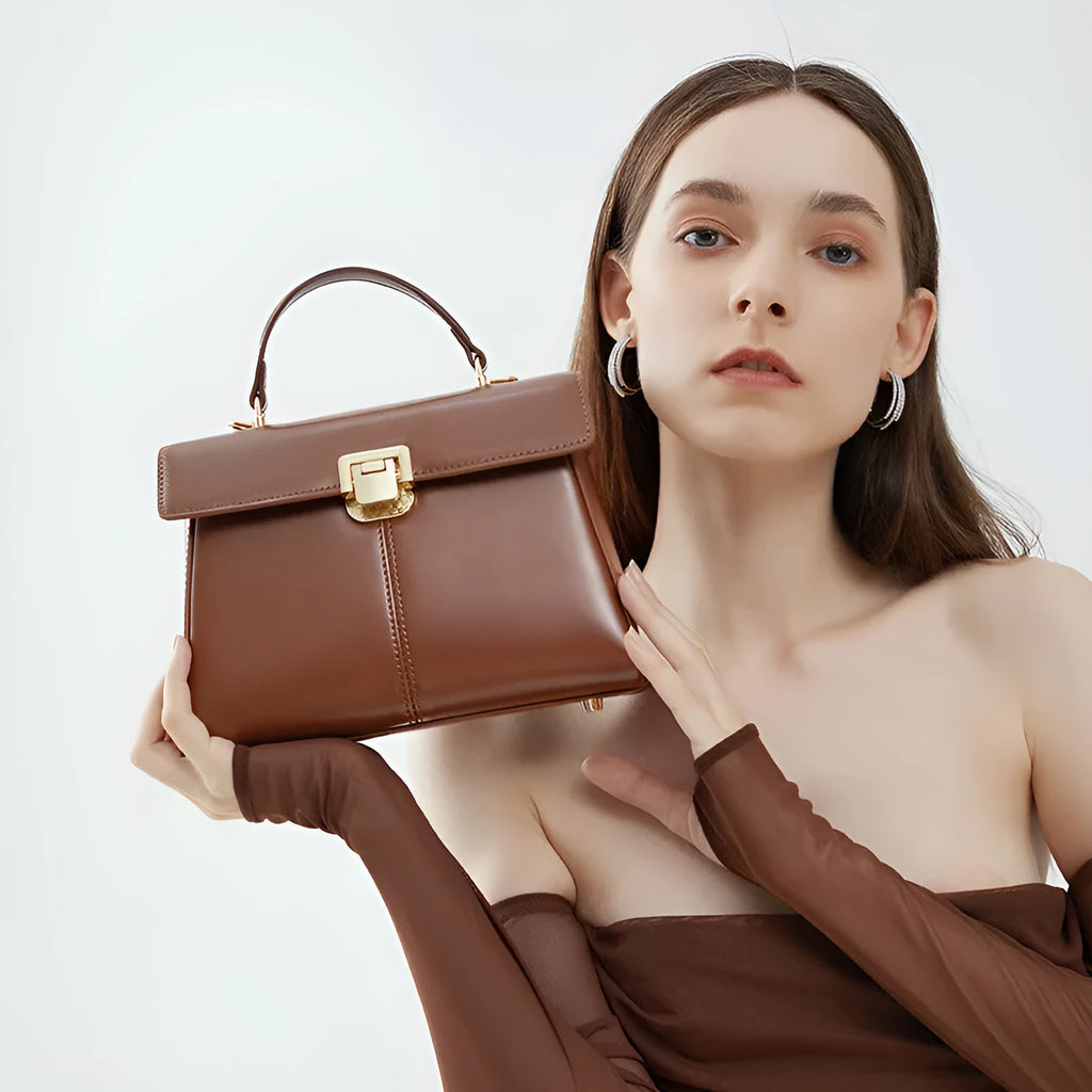 Women's black leather shoulder bag with vachette clasp, showing horizontal square shape and adjustable strap