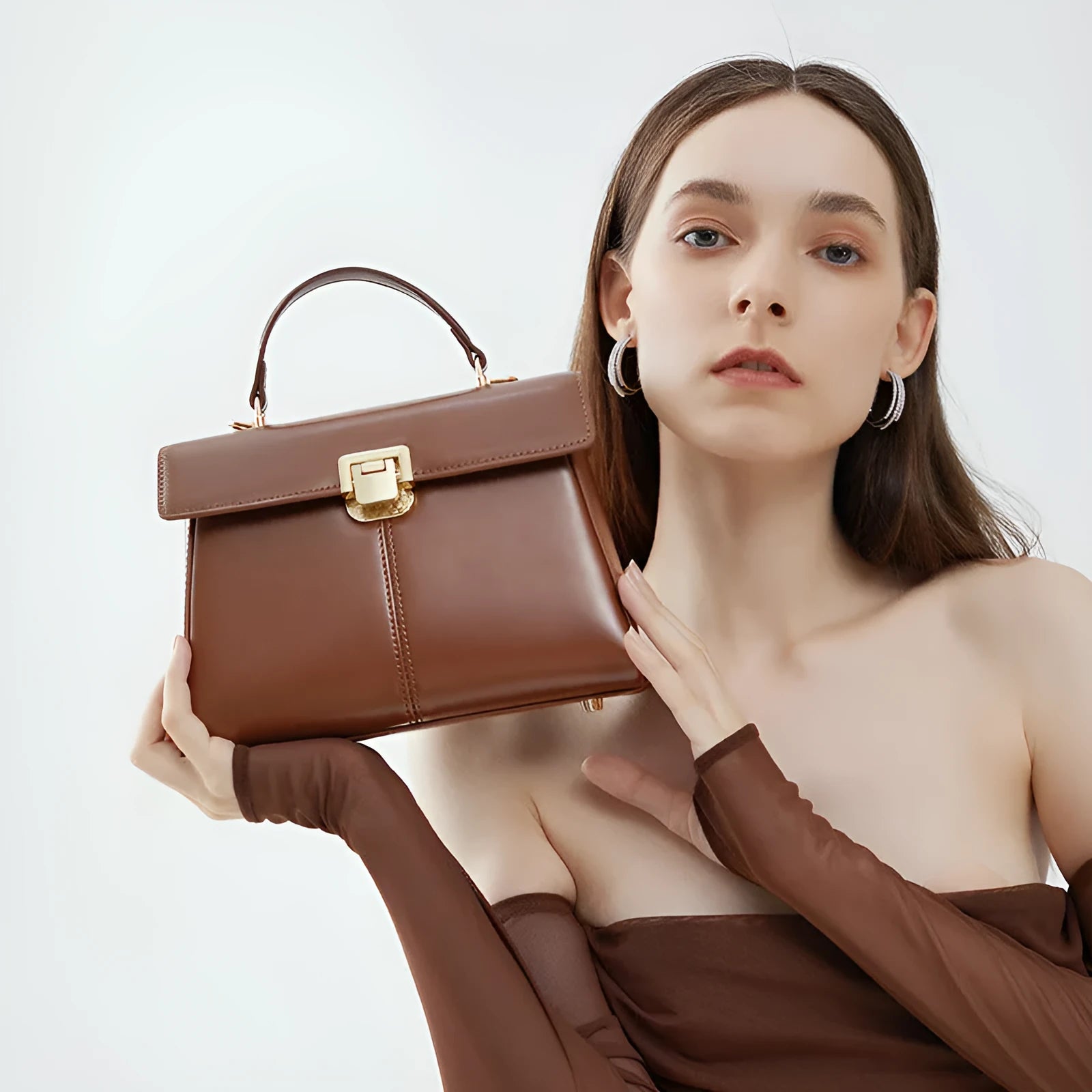 Women's black leather shoulder bag with vachette clasp, showing horizontal square shape and adjustable strap