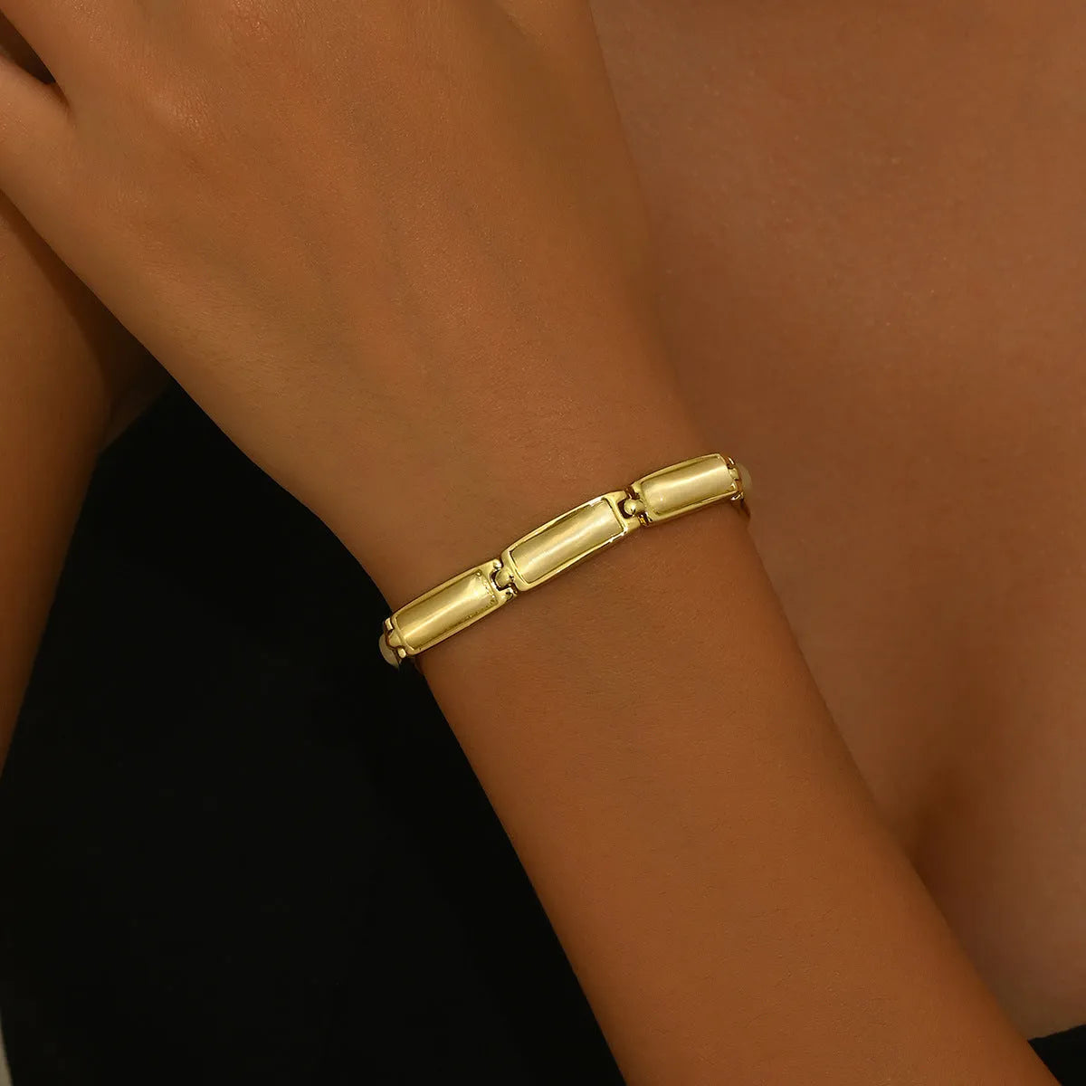 Women's geometric rose gold opal bracelet with quadrilateral shape and gemstone inlay on a plain background