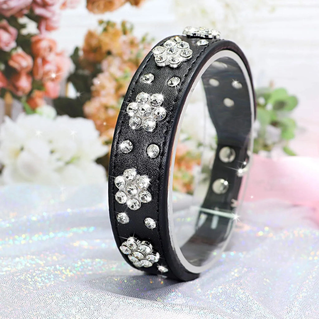 Decorative dog collar made of black PU leather with a pattern of rhinestone flowers and studs, showing the metal D-ring.