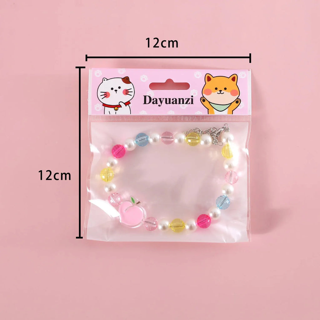 Colourful plastic bead cat necklace in rainbow, peach, or small flower pattern on a white background.