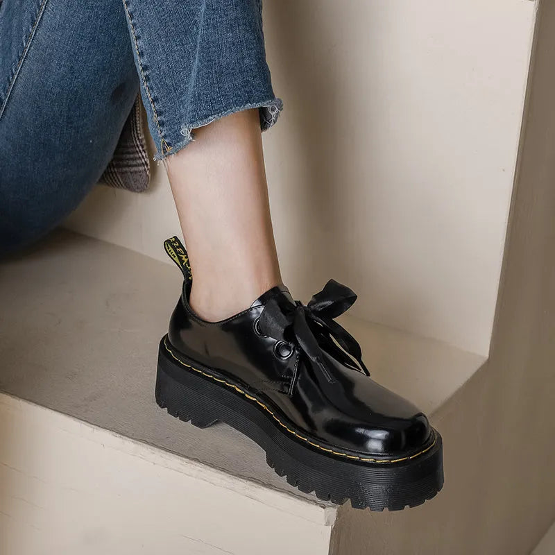 Women's white and black thick soled leather shoes with cross strap and ribbon detail on a superfine fibre upper.
