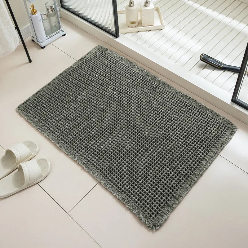 A square, checkered-pattern absorbent bathroom floor mat with a non-slip backing, shown in a neutral colour.