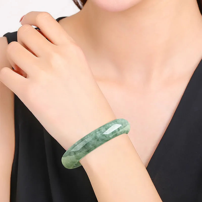 Natural deep pea green emerald stone bracelet on a wrist, showing its simple band design.
