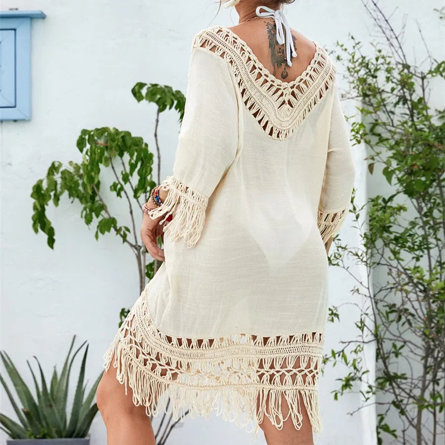 Apricot coloured crocheted knitted patchwork beach dress on a hanger, showing mid-length skirt and half sleeves.