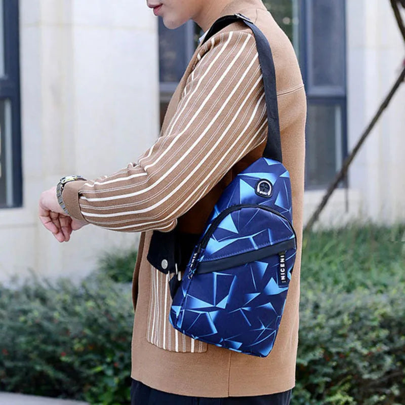 Men's blue Oxford cloth crossbody sling bag showing earphone hole and front zipper.