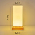 Nordic solid wood base USB table lamp with a white geometric shade on a wooden table.