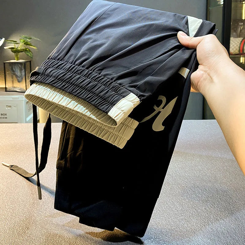 Men's black cropped casual trousers with an ankle band made from thin cotton fabric.